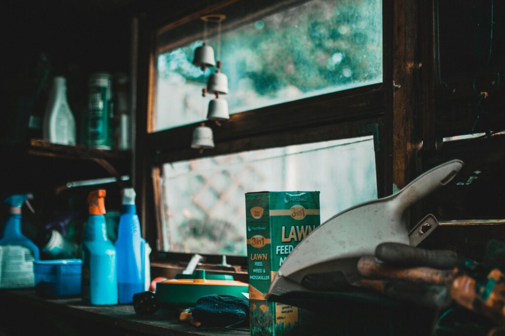 pexels-photo-1456326-1456326 A cozy indoor garden shed scene with tools and lawn supplies by a window.